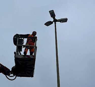 Arbeiter auf Hebebühne an einer Straßenlaterne